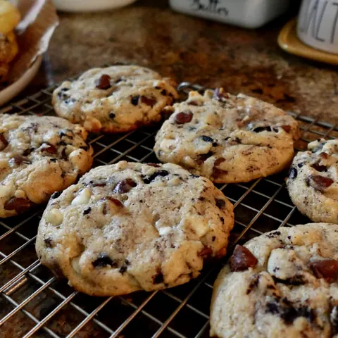 Thick cookies loaded with dark and white chocolate pieces on a cooling rack