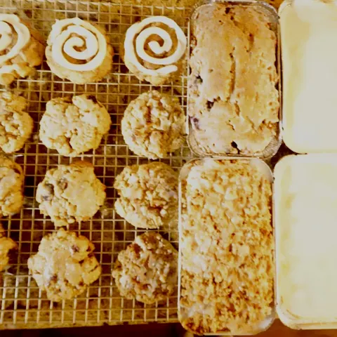 Overhead view of cookies with cinnamon-roll icing swirls beside a streusel-topped loaf