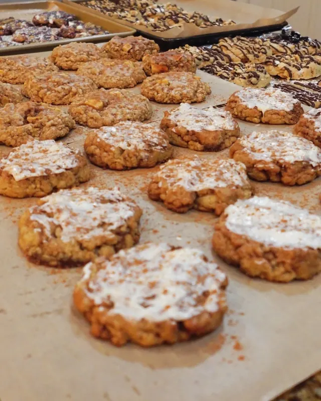 Rows of cinnamon-dusted iced cookies and oatmeal cookies cooling on parchment in Madison's kitchen